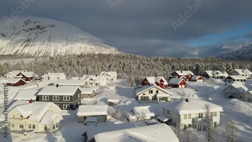 The flight above snow-covered village in forest in winter