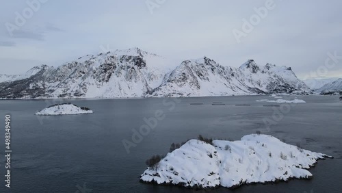 The flight above sea and small islands surrounded by mountains in winter