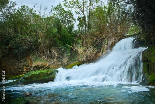 A beautiful waterfall in a forest with blue water and trees. High quality nature photo. 