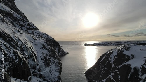 The flight  in fjord surrounded by rocky mountains towards sun in winter