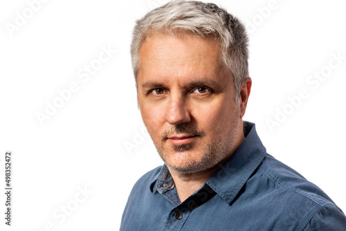 Head and shoulders portrait of a bearded middle-aged man looking thoughtfully at the camera over a white studio background with copy space