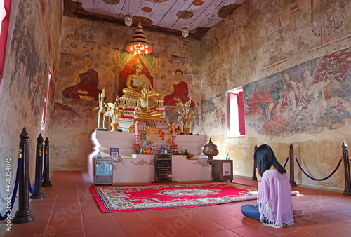 A Woman Praying in Gorgeous Old Ordination Hall of Wat Chomphuwek Buddhist Temple, a National Ancient Monument in Nonthaburi, Thailand photo