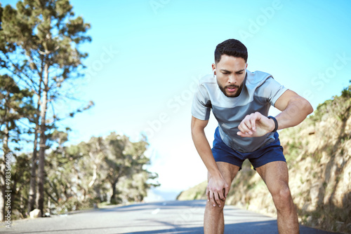 Working towards becoming a winner. Shot of a sporty young man checking his wristwatch while exercising outdoors.