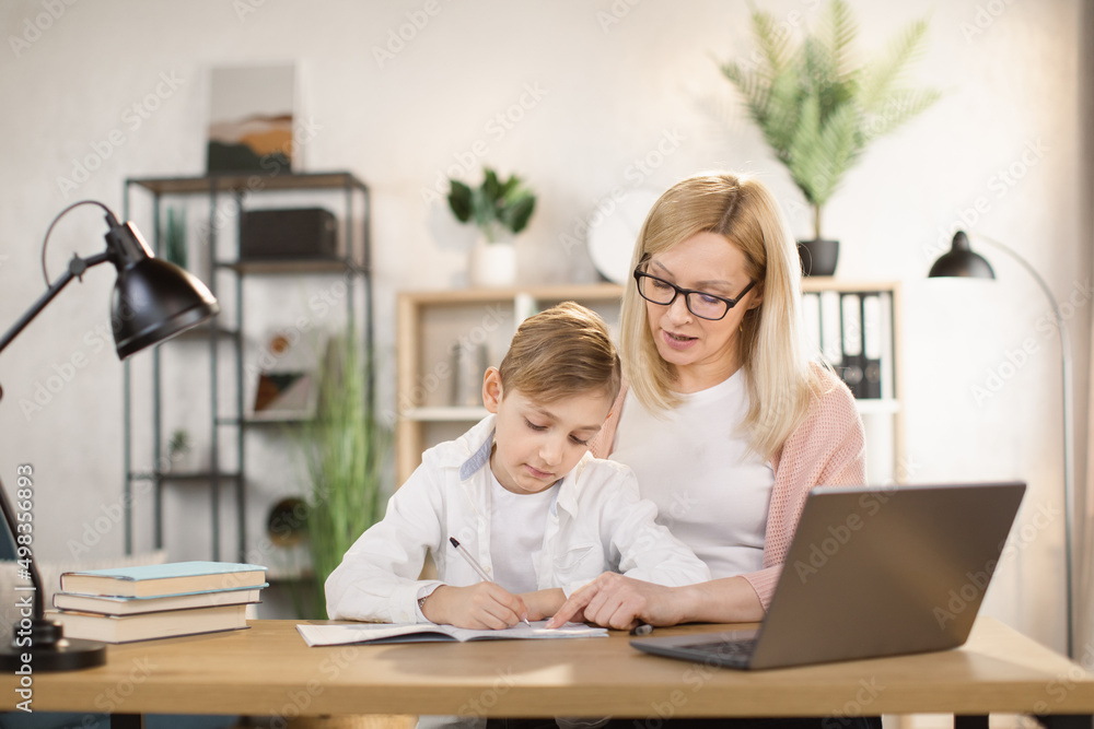 Mother helping his son with his homework at home. Social distancing and self isolation in quarantine lockdown for Coronavirus Covid19 Mother helping his son with his homework at home. Social distancing and self isolation in quarantine lockdown for Coronavirus Covid19