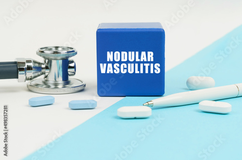 On a white and blue surface are pills, a stethoscope, a pen and a cube with the inscription - Nodular vasculitis photo