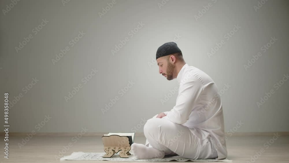 Middle Eastern man praying closeup, reading quran on floor, islamic