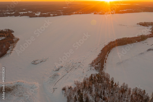 Sunrise over forest and ice-covered lake.Early sunrise in winter. Drone photo. Scandinavia. Finland.
