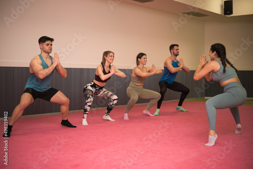 A group of young people practice yoga in a gym room.