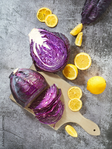 Overhead view of sliced raw red cabbage on cutting board with lemons. Kitchen colorful scene. Top view. 