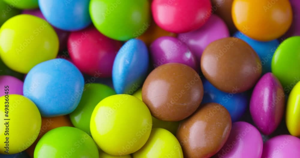 Slow motion close-up of round colorfull chocolate candies, dragee. Rotation and fall multicolored chocolate candies Slow motion close-up of round colorfull chocolate candies, dragee. Rotation and fall multicolored chocolate candies