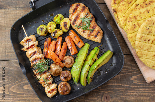 Grilled chicken steak with different  vegetables on a pan. Top view, flat lay