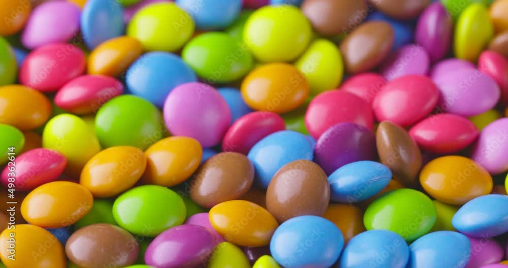 Slow motion close-up of round colorfull chocolate candies, dragee. Rotation and fall multicolored chocolate candies Slow motion close-up of round colorfull chocolate candies, dragee. Rotation and fall multicolored chocolate candies