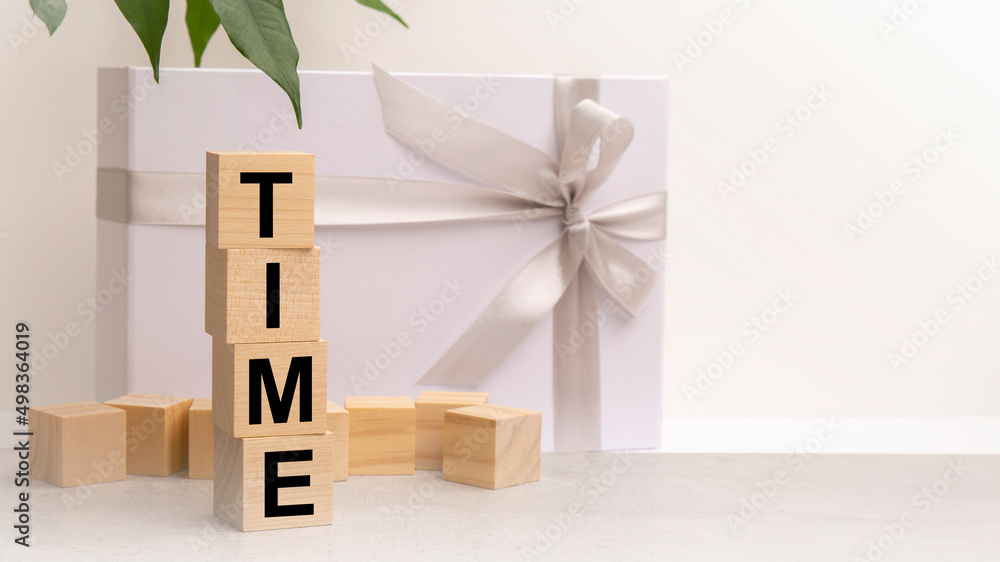 Obraz premium Time word made with building blocks on the table next to a flower and a gift box