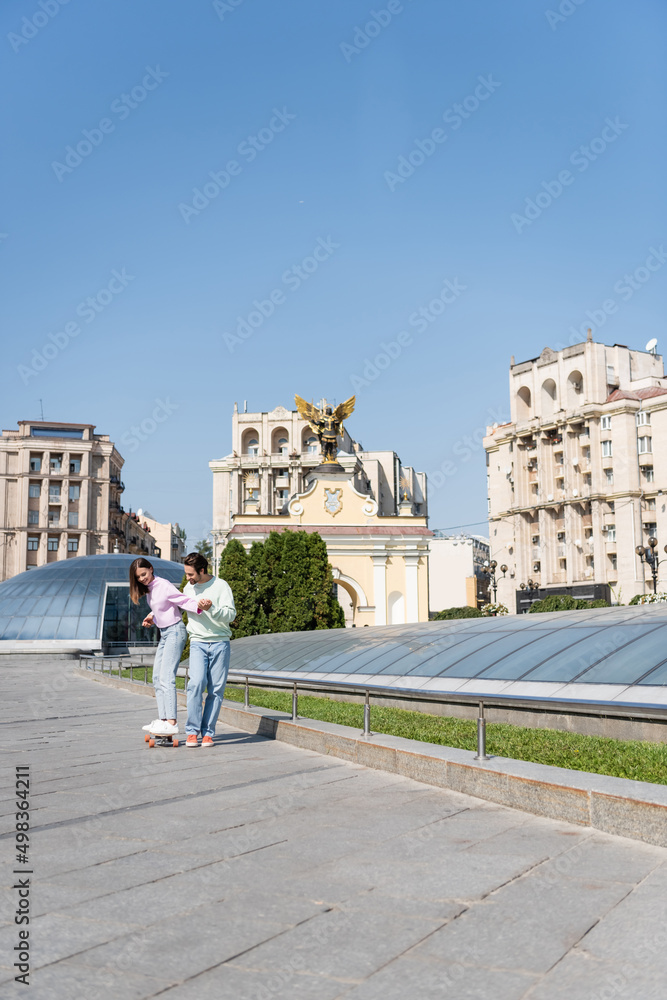 KYIV, UKRAINE - SEPTEMBER 1, 2021: Smiling couple riding penny board on urban street, Independence Square.