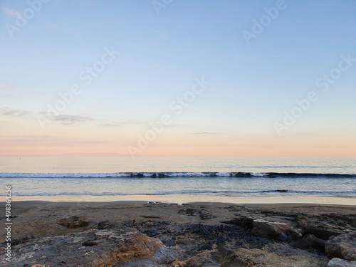 Horizontal photo of a soft pink sunset with a long small wave