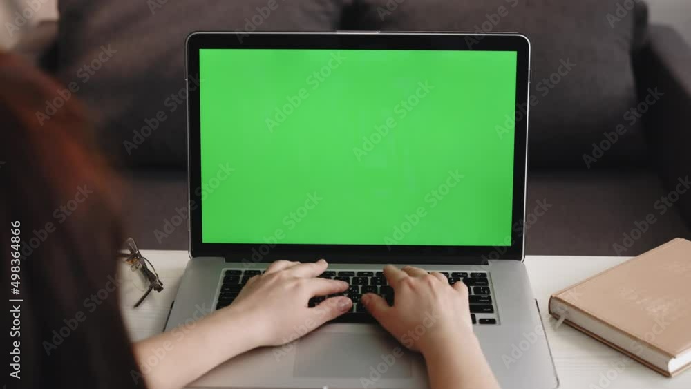 Unrecognizable Person Close-up Shot Woman Uses Laptop with Green Mock-up Screen While Sitting at the Desk in His Cozy Living Room Unrecognizable Person Close-up Shot Woman Uses Laptop with Green Mock-up Screen While Sitting at the Desk in His Cozy Living Room
