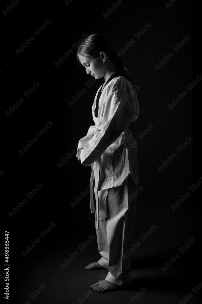Woman in kimono practicing taekwondo on black background. Woman in kimono practicing taekwondo on black background.