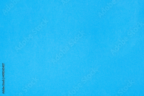 Paper background in plain blue color with a fibrous texture. Paper background in blue color with empty space for text or advertisement. Uniform paper texture for packaging or background