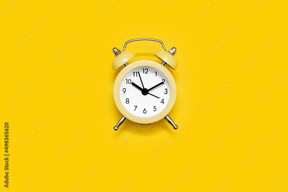 Yellow old-fashioned alarm clock with a dial on a yellow background. The concept of time and responsibility. Vintage look of the alarm clock Yellow old-fashioned alarm clock with a dial on a yellow background. The concept of time and responsibility. Vintage look of the alarm clock