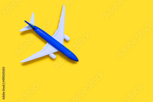 Airplane model on a yellow background with free space for text or advertising. Tourism or freight transport concept. Toy airplane on a yellow background with a top view
