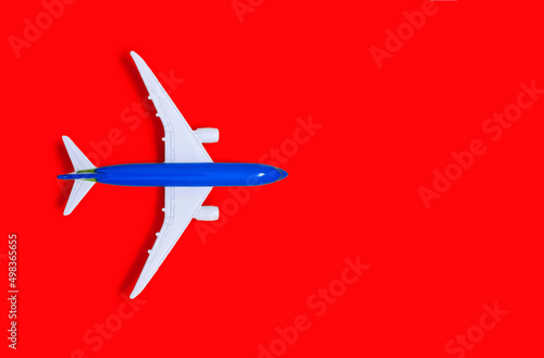 Airplane model on a red background with free space for text or advertising. Tourism or freight transport concept. Toy airplane on a red background with a top view