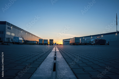 Konstfotografi Logistics area with halls and trucks at sunset