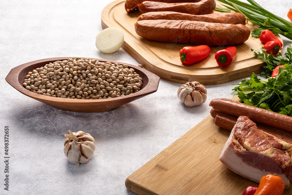 Fototapeta premium ingredients for preparing a recipe, dried meat, bacon, cabbage, red bell pepper, sausage, parsley, on a table