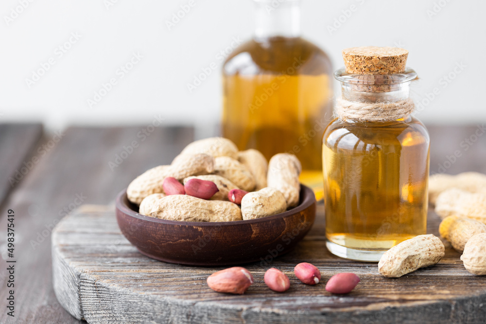 Concept of organic vegetable oils for cooking and cosmetology. Peanut nuts to illustrate ingredients. Rustic wooden background, pure natural oil in glass bottles. Close up, macro. Concept of organic vegetable oils for cooking and cosmetology. Peanut nuts to illustrate ingredients. Rustic wooden background, pure natural oil in glass bottles. Close up, macro.