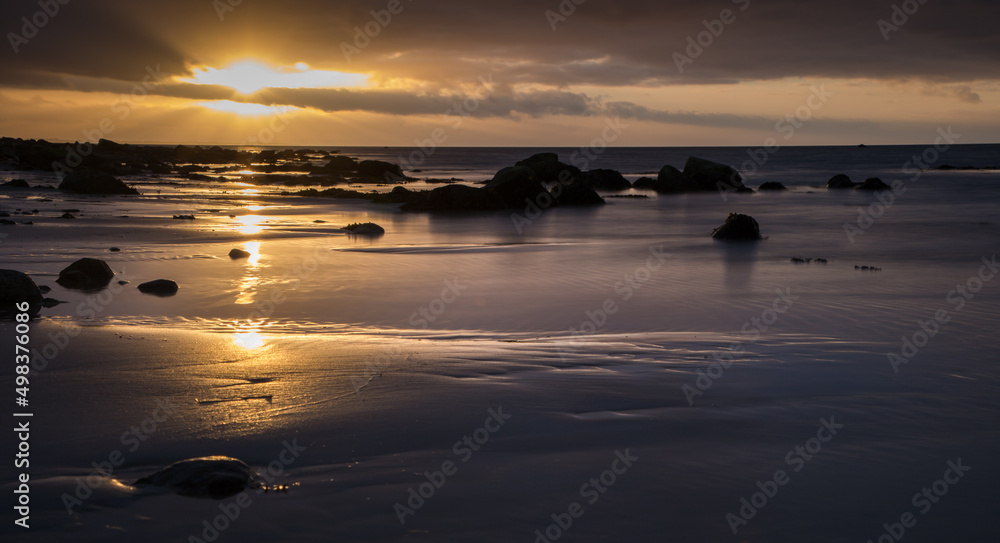 sunset on an empty sandy beach with stones