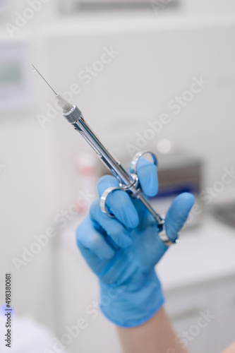 Hand of dentist holding dental syringe