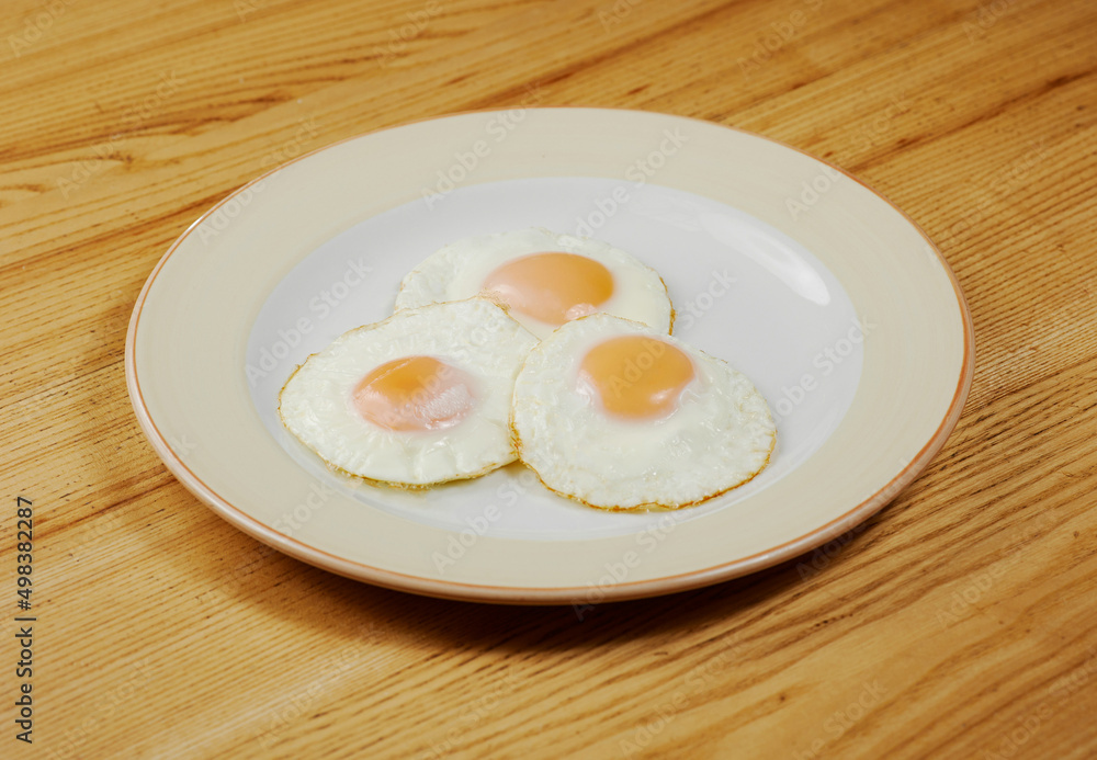 fried scrambled eggs from three eggs on a wooden table fried scrambled eggs from three eggs on a wooden table