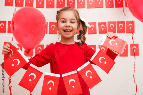 Portrait of small baby girl with Turkish flag. Cute little child celebrating Turkish National Sovereignty and Children's Day or Commemoration of Atatürk Youth and Sports Day. Red white colors concept. photo