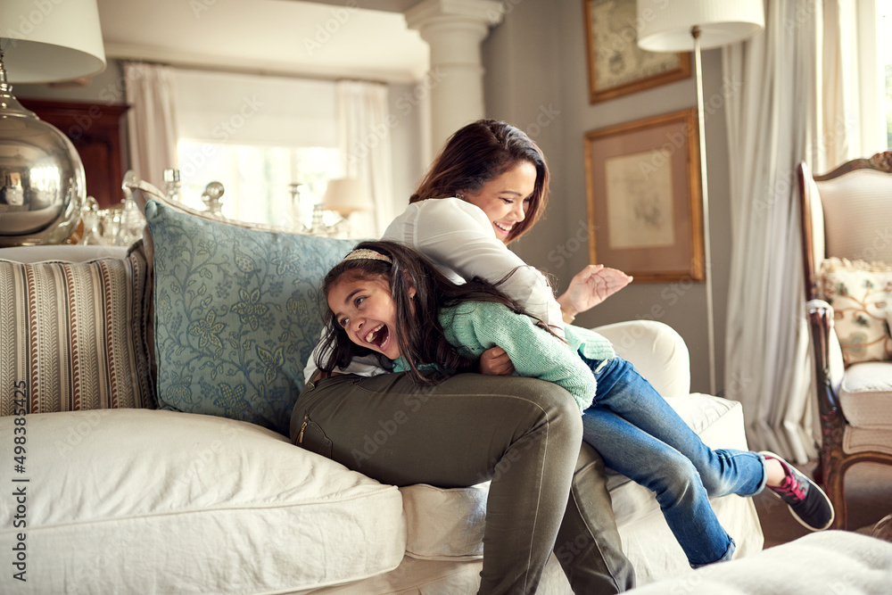 Mother and daughter moments filled with fun. Shot of a mother and daughter having fun on the sofa at home. Mother and daughter moments filled with fun. Shot of a mother and daughter having fun on the sofa at home.
