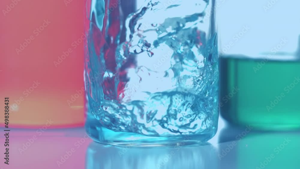 Animation of red dots floating over blue reagent pouring into glass Animation of red dots floating over blue reagent pouring into glass