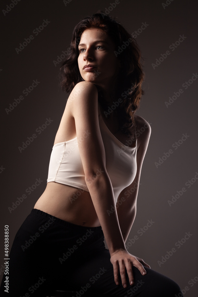 Fototapeta premium Beautiful teenage girl studio portrait against dark background..