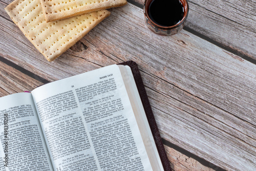 Photography Unleavened bread (matzo), a cup of red wine, and open the Holy Bible Book on a wooden table with copy space