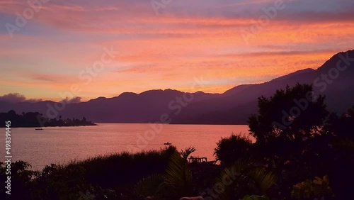 Lake Atitlán Santiago Guatemala | A beautiful sunset of Lake Atitlan with a Mayan boat moving slowly in the center of the lake photo