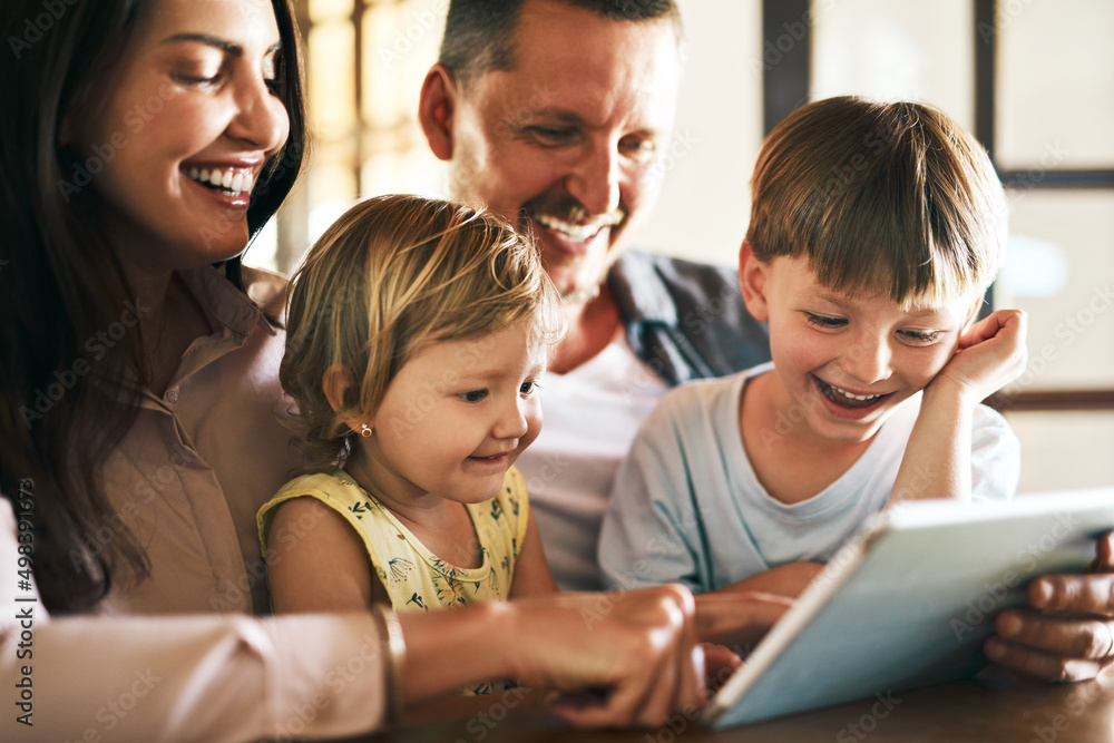 Adding screen time to family time. Shot of a young family of four using a digital tablet together at home. Adding screen time to family time. Shot of a young family of four using a digital tablet together at home.