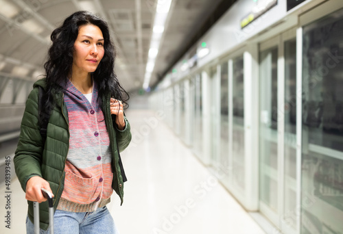 Positive female traveler waiting train on platform of subway station, using public transport in big city © JackF