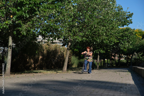 Wallpaper Mural Latin mature woman practicing on her electric kick scooter, modern transport Torontodigital.ca