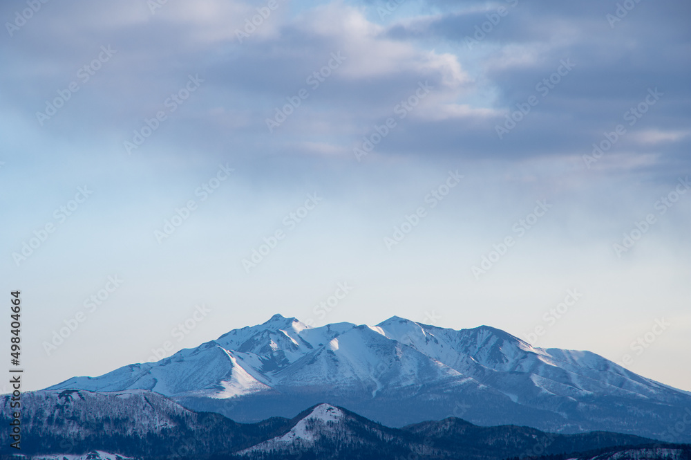 朝の遠くの雪山の稜線。日本の北海道の斜里岳。