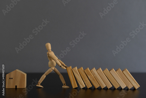 Wooden puppets stop falling wooden blocks and business interruption strategy ideas. Solutions. Close the hands of businessmen. Stop the risk of falling trees on the table.