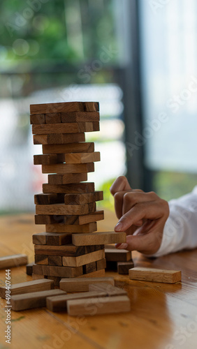 The girl's hand tried to pull out the wooden block without causing the tower to overturn. skill group game Construction business risk concept. Close-up photo with space for text next to it.