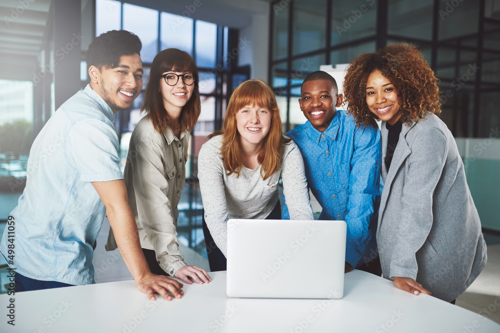 Modern technology gives up the edge. Cropped portrait of a group of young businesspeople huddled around a laptop in their office.