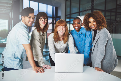 Modern technology gives up the edge. Cropped portrait of a group of young businesspeople huddled around a laptop in their office.