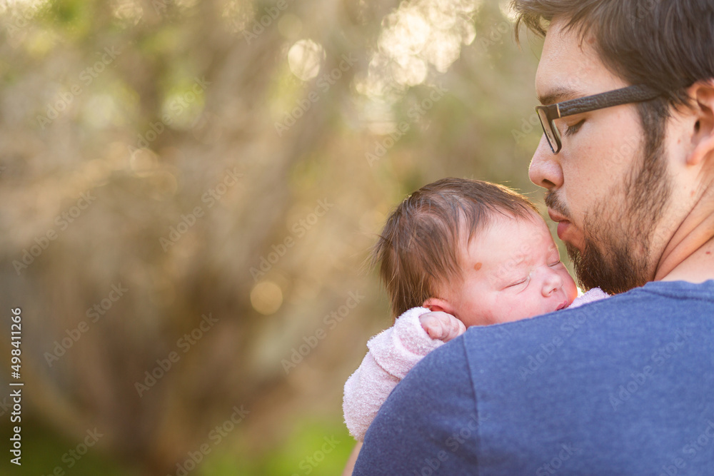 Young father kissing his newborn daughter outside with bokeh copy space Young father kissing his newborn daughter outside with bokeh copy space