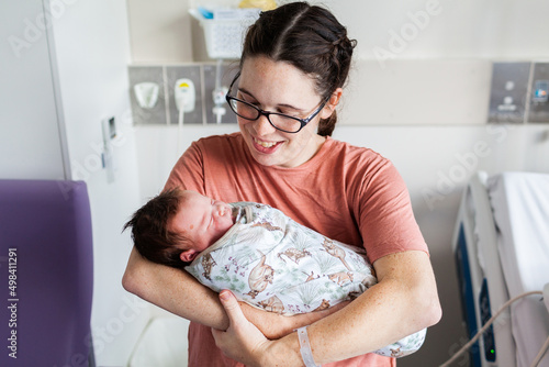 Young parent holding newborn baby in hospital maternity ward after delivery photo