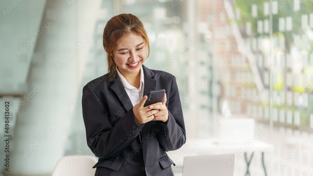 Charming young Asian business woman with a smile sitting using smartphone at the office. Charming young Asian business woman with a smile sitting using smartphone at the office.