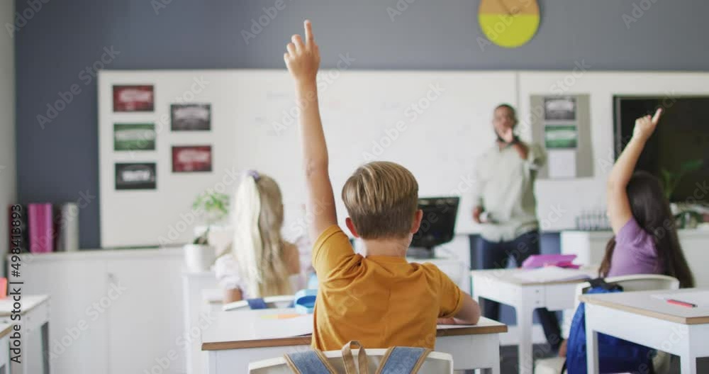 Video of back view of diverse pupils raising hands in classroom during ...