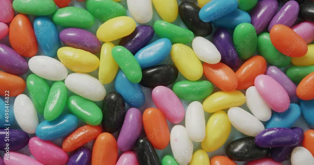 Video of close up of multi coloured sweets over blue background Video of close up of multi coloured sweets over blue background